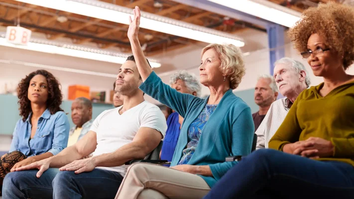 Woman Asking Question At Neighborhood Meeting In Community Center